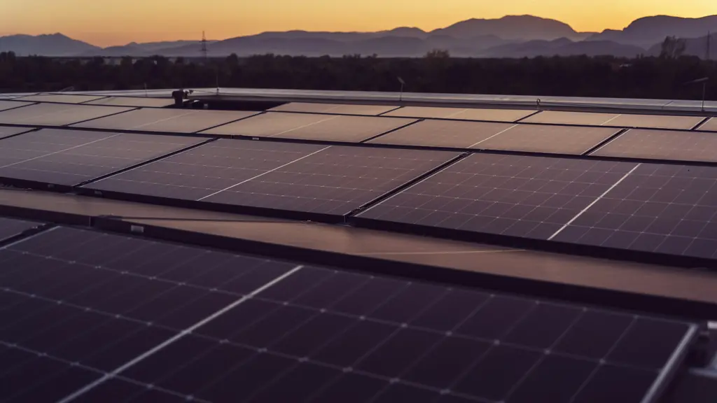 Rooftop solar panels catching the last of the evening sun, with hills on the horizon