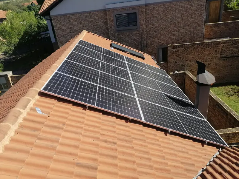 Black solar panels installed on a terracotta tiled roof of a brick home